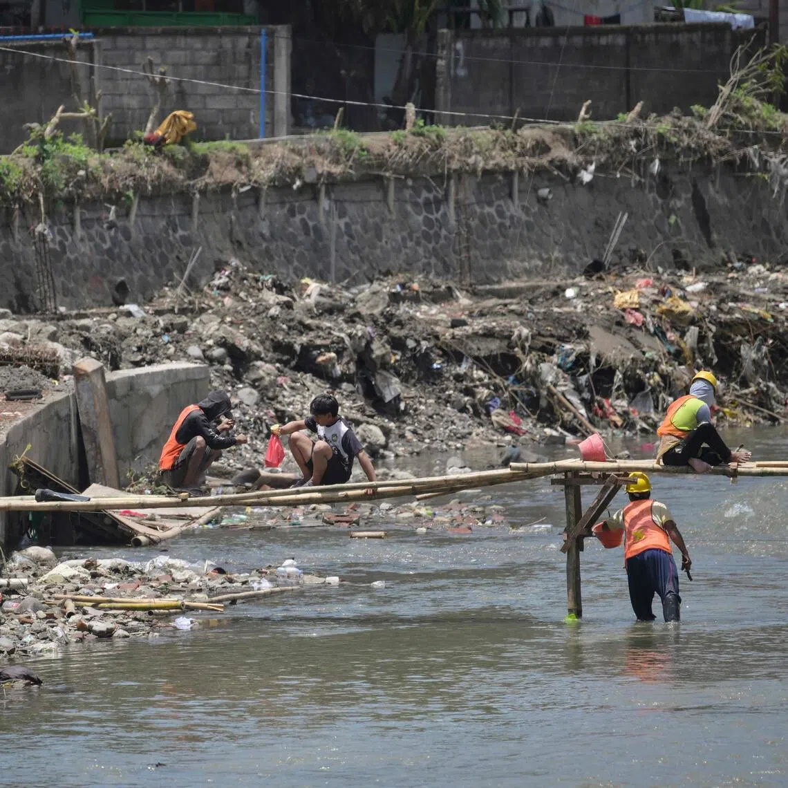 Workers repairing an embankment of the Badung River which was damaged by flooding in Denpasar, on Indonesia's resort island of Bali, on Oct 1.