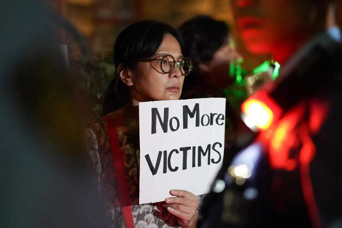 A woman holds a sign at a protest against the killing of a woman in Okinawa allegedly committed by a US Marine, in front of the US Embassy in Tokyo on October 6, 2026. A woman's murder allegedly committed by a US Marine in Okinawa is a "heinous crime", Japan's premier said on October 5, as the new accusation of violence involving American forces sparked public outrage. (Photo by CHRISTOPHER JUE / AFP)