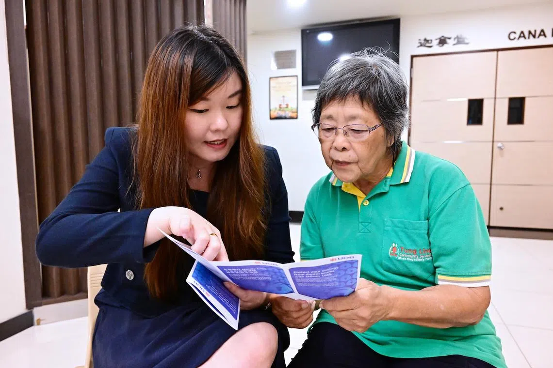 Ms Tan Pei Xin (left), assistant branch manager of UOB’s Parkway Parade branch, explaining the money lock feature to Mdm Margaret Yeo.