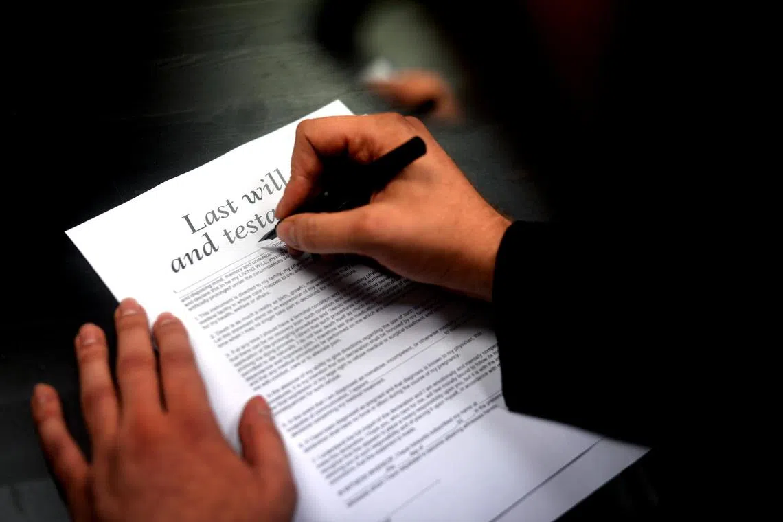 Posed photo of a peron writing on a piece of paper with the subject heading "Last will and testament" to illustrate an article on a will-writer.