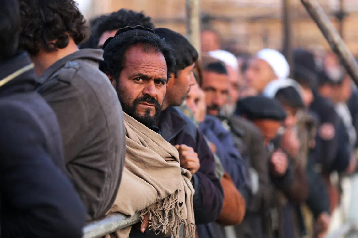 Afghan men stand in line to receive food aid from a non-governmental organisation in Kabul on Dec 25, 2022.