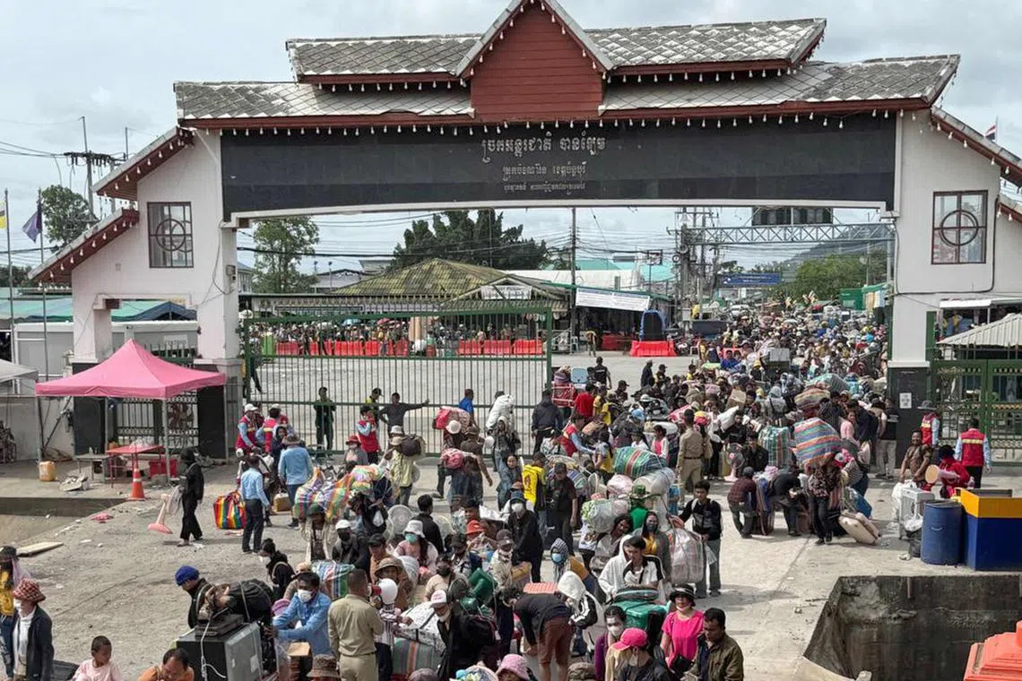 Cambodian migrant workers carrying their belongings as they returned from Thailand following border clashes through the Daung International Border Gate in Battambang province.  