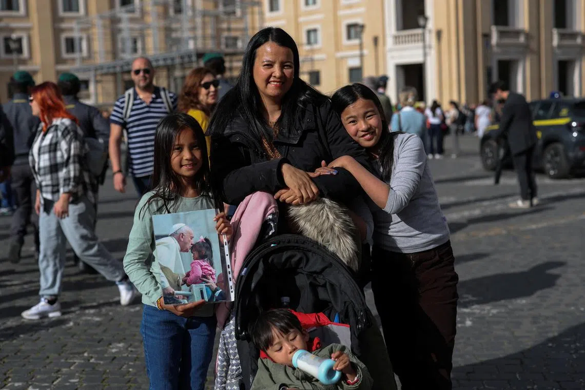 Francezka Abano, 9, holds a picture of her and Pope Francis from 2018, as she poses for a picture with her mother Diane Karla Abano, her sister Sophia, 9, and her brother John Florence, 2, in Rome, Italy, April 24, 2025. REUTERS/Hannah McKay