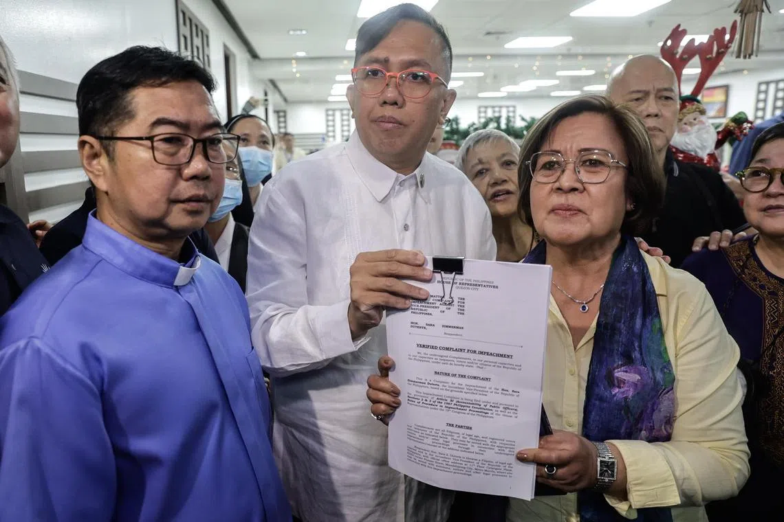 Former senator Lilia de Lima holds a copy of an impeachment complaint against Vice-President Sara Duterte on Dec 2.