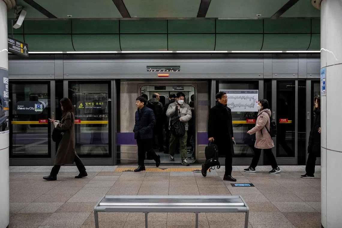 Morning commuters disembark a subway train in Seoul, a day after President Yoon Suk Yeol briefly declared martial law.