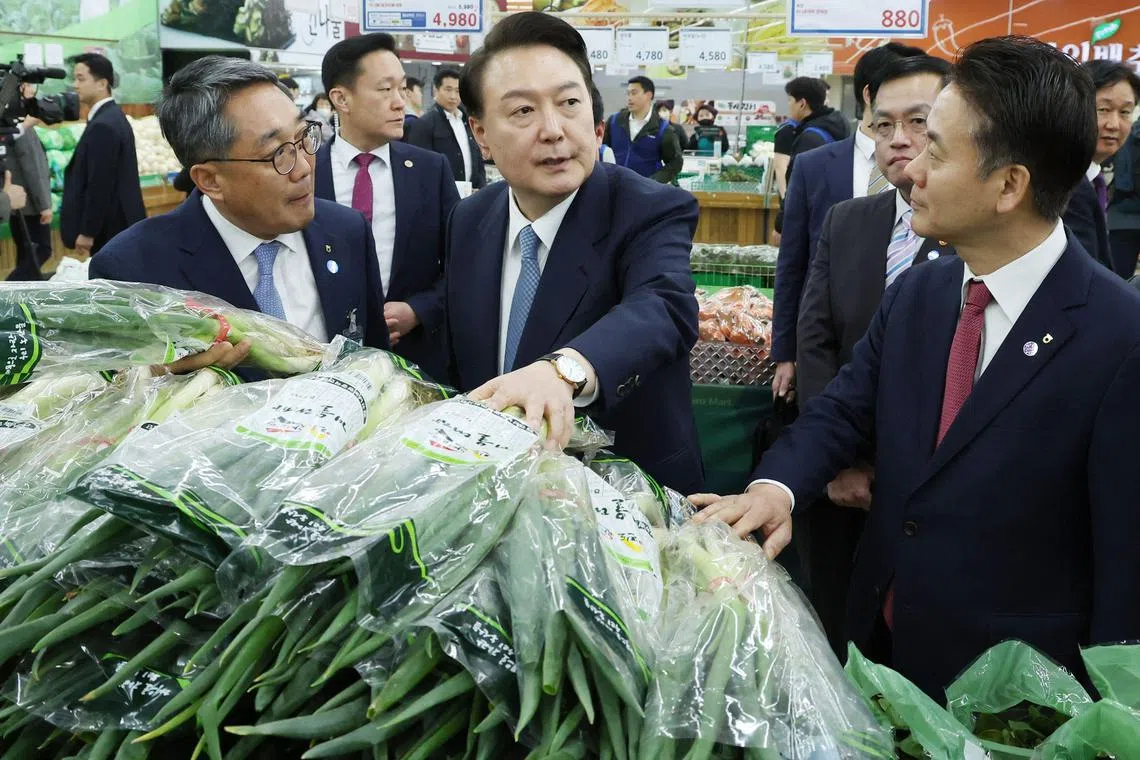 This picture taken on March 18, 2024 shows South Korean President Yoon Suk Yeol (C) visiting a Hanaro Mart branch to check the price of green onions in Seoul. The price of green onions, striking junior doctors, and the president's performance after two years in office are set to dominate voter decisions when South Koreans go to the polls this week. (Photo by YONHAP / AFP) / - South Korea OUT / NO ARCHIVES -  RESTRICTED TO SUBSCRIPTION USE
TO GO WITH AFP STORY  SKorea-election-politics