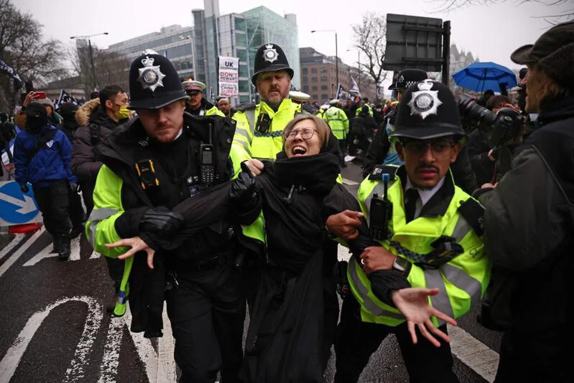 Police officers take away a protester who was attempting to block the road during a gathering at the site of the former Royal Mint in London on February 8, 2025, to demonstrate against a proposal to move China's embassy to this site, a stones-throw from The Tower of London. As Britain's new Labour government bids to reset long-fraught ties with China amid a suspected spy scandal, another issue could prove thorny: Beijing's contentious plans to open the largest embassy in the UK. China has for several years been trying to relocate its embassy, to a sprawling historic site in the shadow of the Tower of London. (Photo by HENRY NICHOLLS / AFP)