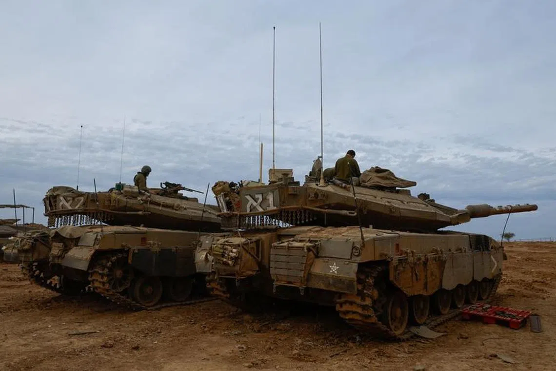 Israeli soldiers sit in Merkava tanks near the Israel-Gaza border, during a temporary truce between Hamas and Israel, in southern Israel, November 25, 2023. REUTERS/Alexander Ermochenko