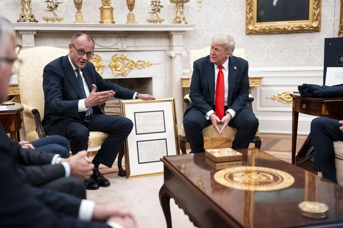 German Chancellor Friedrich Merz (left) presenting US President Donald Trump with a framed birth certificate of Mr Trump's  grandfather, in the Oval Office of the White House on June 5.