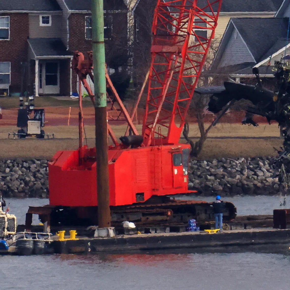 FILE PHOTO: A crane retrieves part of the helicopter from the Potomac River, in the aftermath of the collision of American Eagle flight 5342 and a Black Hawk helicopter that crashed into the river, by the Ronald Reagan Washington National Airport, in Arlington, Virginia, U.S., February 6, 2025. REUTERS/Eduardo Munoz/File Photo