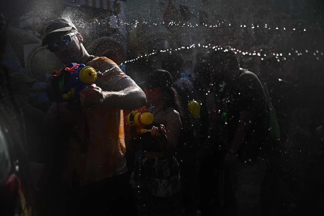 TOPSHOT - Revellers take part in mass water fights on the eve of the Songkran, or Thai New Year, on Khao San Road in Bangkok on April 12, 2026. (Photo by Lillian SUWANRUMPHA / AFP)