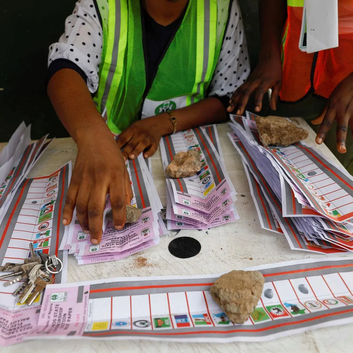 Electoral officials use stones to hold down ballots during the vote counting process of the gubernatorial election at a polling unit in Lagos, Nigeria March 18, 2023. REUTERS/Temilade Adelaja