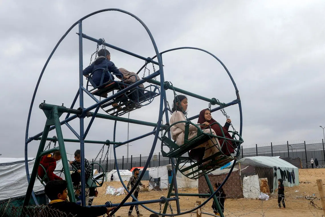 Displaced Palestinian children, who fled their houses due to Israeli strikes, playing on swings at a camp at the border with Egypt, amid fears of an Israeli ground assault in Rafah, in the southern Gaza Strip, on Feb 18, 2024. 