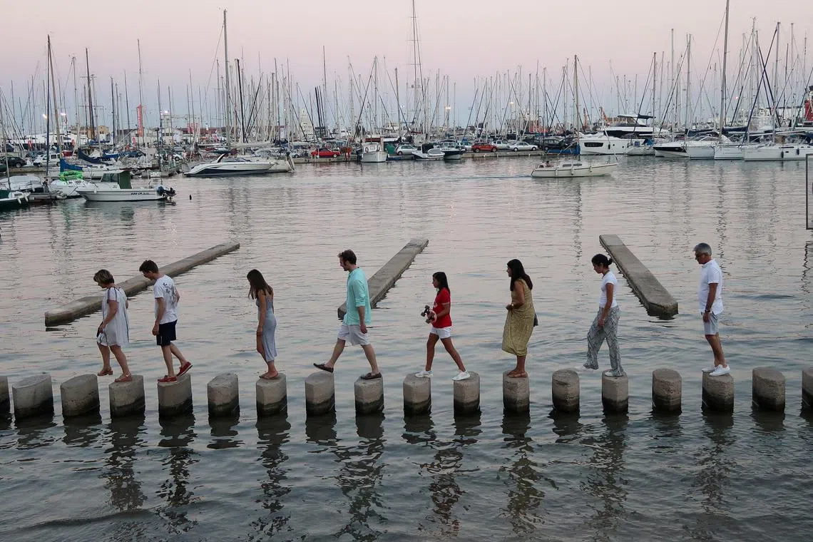 People walk across concrete posts to cross a section of the Marina in Palma de Mallorca, Spain, July 28, 2018.  REUTERS/Paul Hanna/File Photo