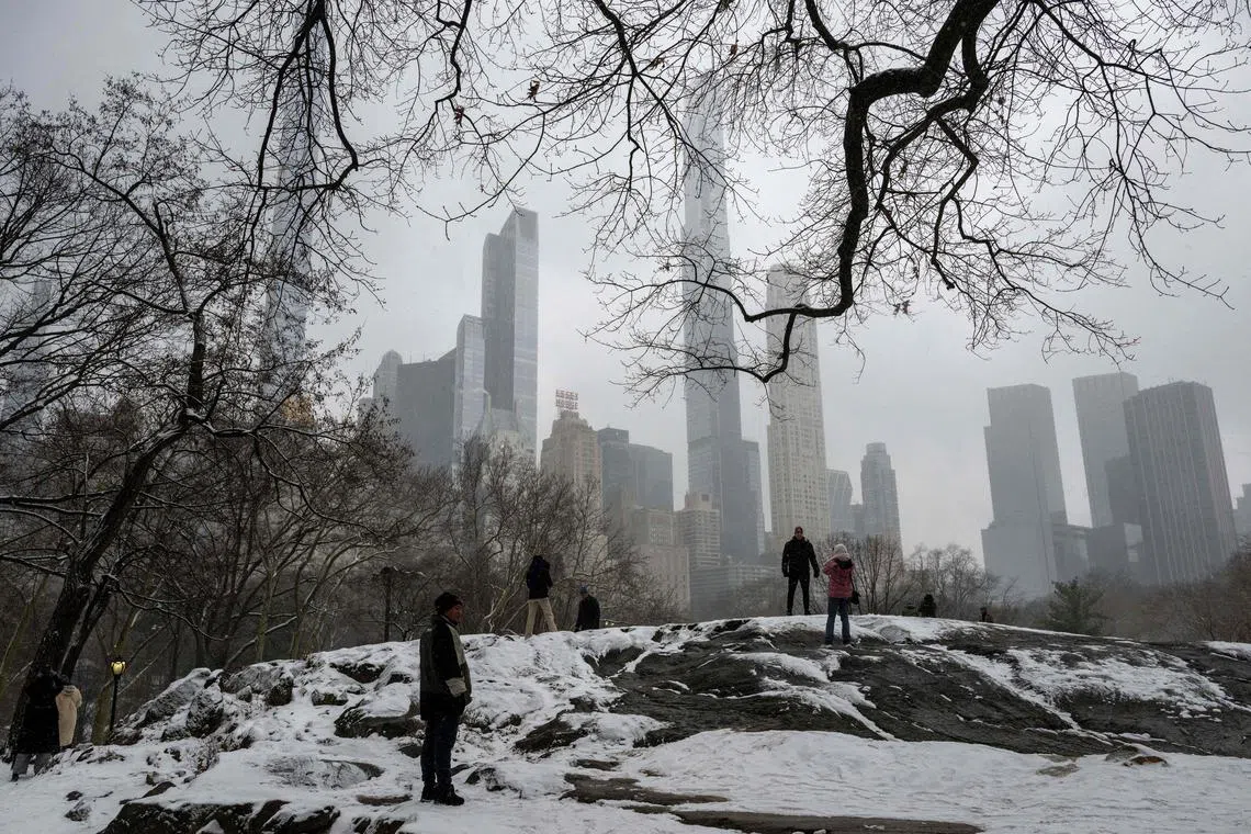 People walk through New York's Central Park as snow falls during a winter storm on January 19, 2024.