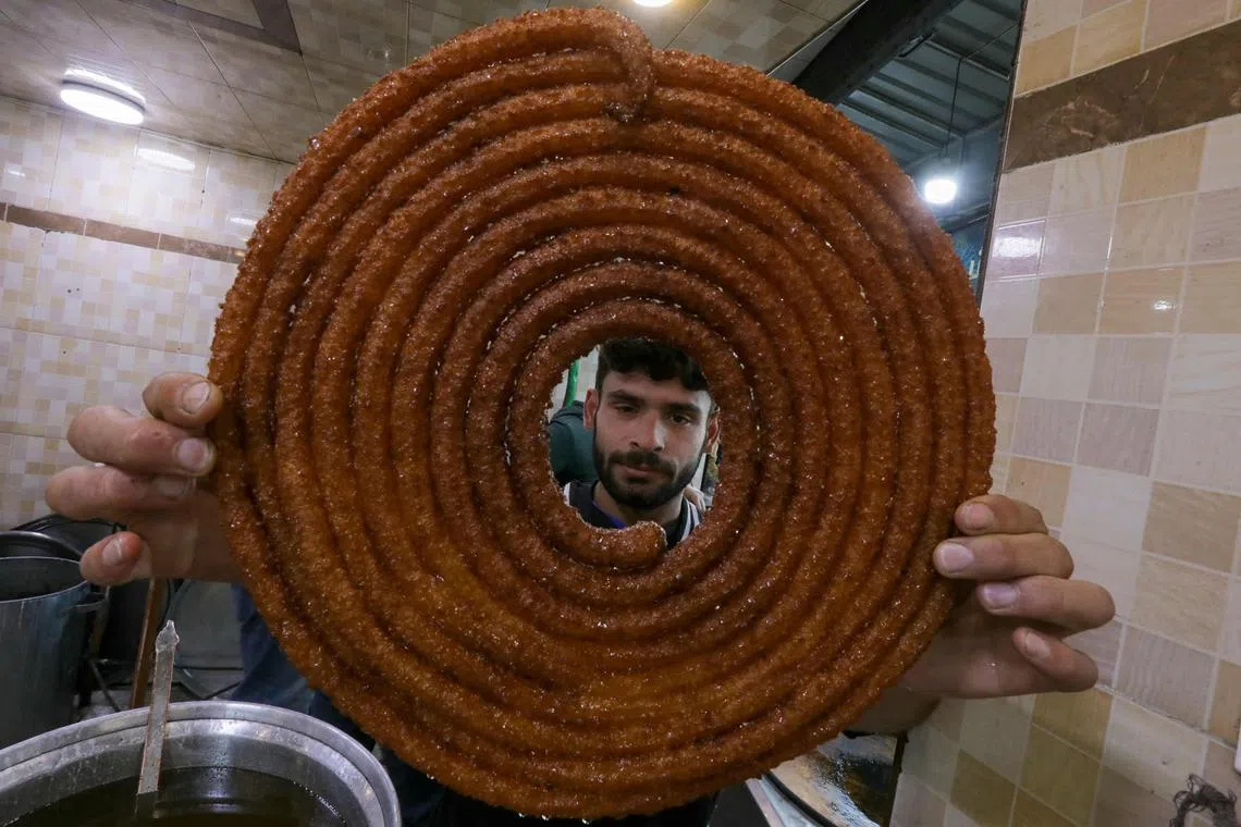 A man preparing fried sweets for iftar (breaking of the fast) on the first day of the Muslim holy fasting month of Ramadan in the northern Syrian city of Al-Bab on Mar 11, 2024. 