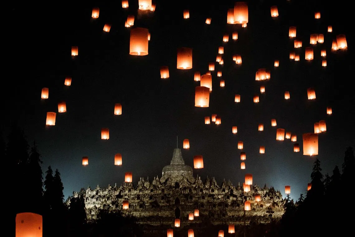 Buddhist devotees releasing lanterns in front of Borobudur Temple, the world's largest Buddhist monument and a UNESCO World Heritage Site, in Magelang, Central Java, on May 12, 2025, as they commemorate Vesak Day. 