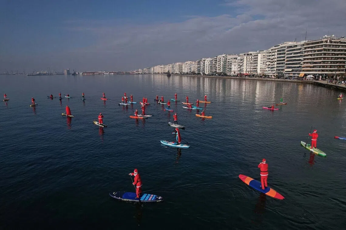 Members of the ThesSUP team (stand-up paddleboarding), wearing Santa Claus costumes, paddling at the seafront of Thessaloniki, Greece, Dec 21, 2025. 