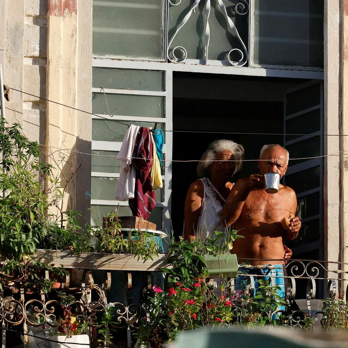 FILE PHOTO: People stand on a balcony before the Cuban government presents far-reaching economic measures that could mark the most significant shift toward a market economy since the 1959 revolution, in Havana, Cuba June 17, 2026. REUTERS/Norlys Perez/File Photo
