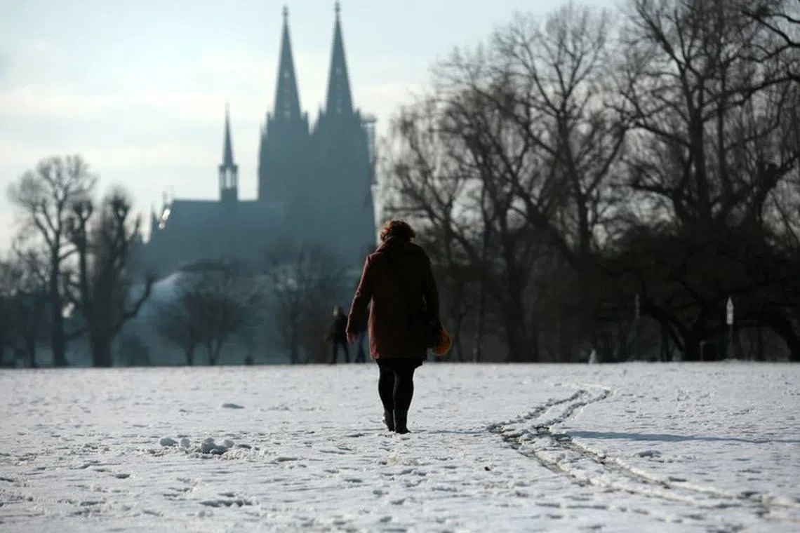 A woman walks through a park covered with snow nearby the Cologne Cathedral amid the spread of the coronavirus disease (COVID-19) in Cologne, Germany, January 24, 2021. REUTERS/Thilo Schmuelgen/ File photo
