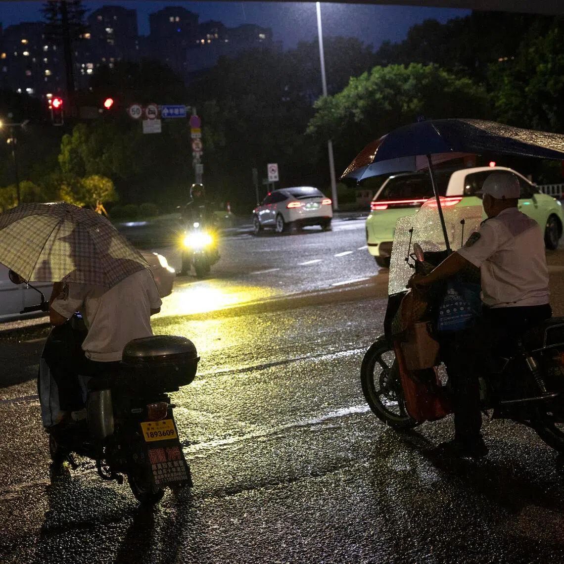 Commuters sheltering while riding their motorbikes in the rain ahead of Typhoon Bavi’s landfall, in Wenzhou, Zhejiang province, eastern China, on July 11.