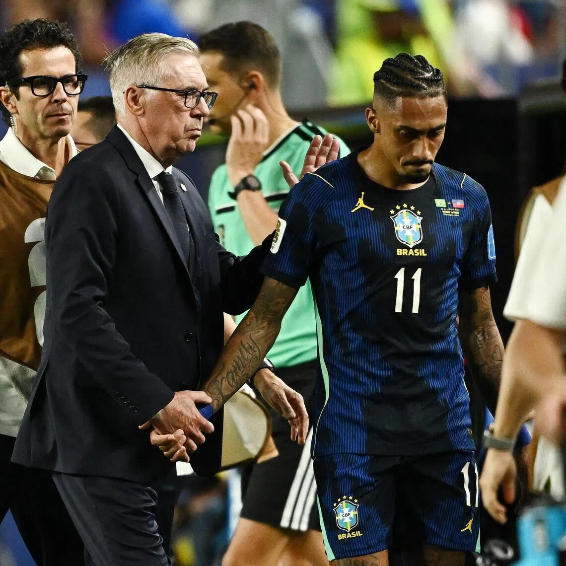 Brazil coach Carlo Ancelotti consoles Raphinha as he walks off the pitch after sustaining an injury.