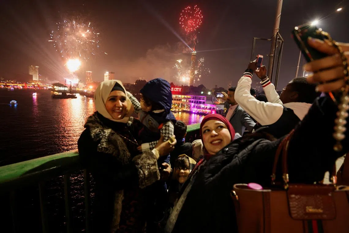 People take pictures as fireworks explode over the Nile River during the New Year celebrations, in Cairo, Egypt, Jan 1, 2023. 