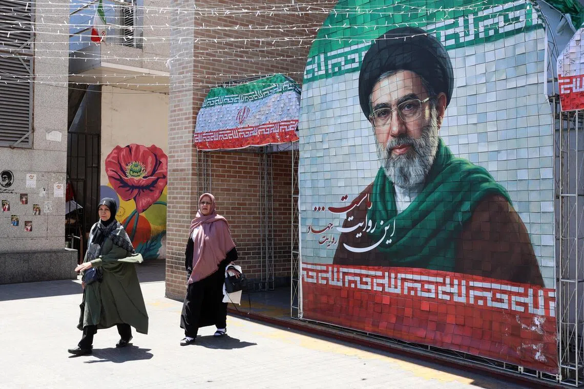 Iranians walking past a picture of the new Iranian supreme leader Ayatollah Mojtaba Khamenei in Tehran on May 18.