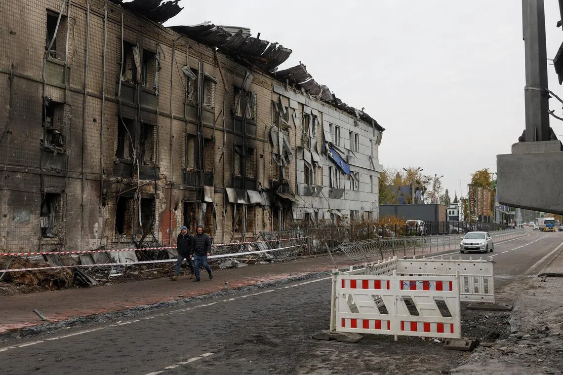 Residents walk past a dealership building in Kyiv hit by a Russian missile strike on Oct 27.