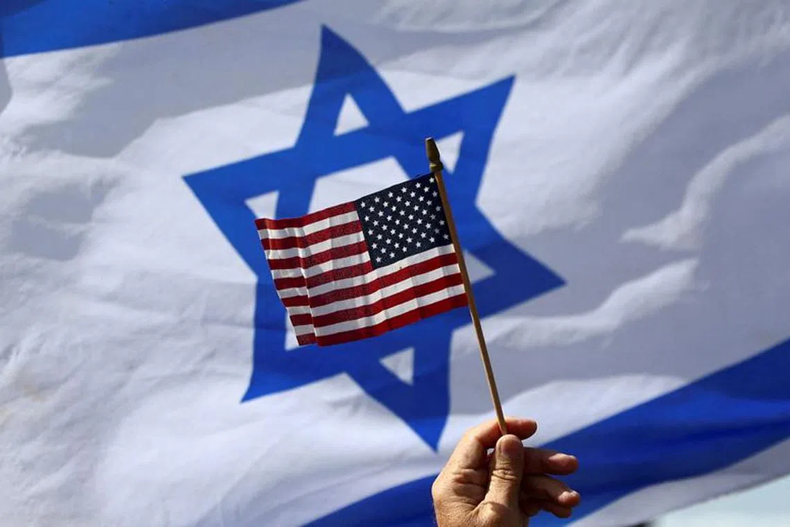 FILE PHOTO: A view of a U.S. flag and an Israeli flag held up by people during a demonstration to show support for U.S. President Joe Biden, for not inviting Israeli Prime Minister Benjamin Netanyahu to the White House, in front of the U.S. Consulate in Tel Aviv, Israel, March 30, 2023. REUTERS/Ronen Zvulun/File Photo