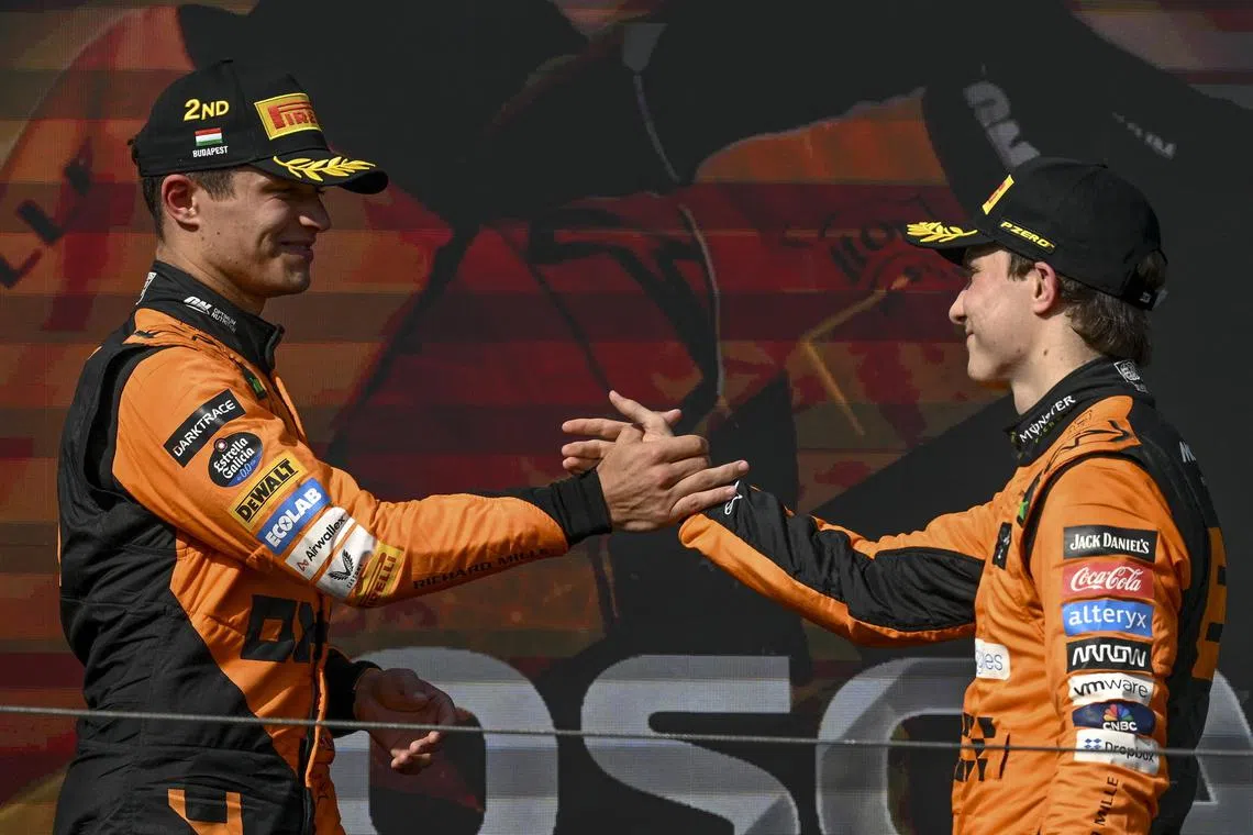 McLaren driver Oscar Piastri of Australia (right) and his teammate Lando Norris celebrate on the podium after the Formula One Hungarian Grand Prix.