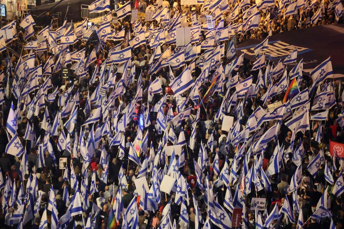 Demonstrators waving flags during a rally to protest the Israeli government's judicial overhaul bill in Tel Aviv on April 22, 2023.