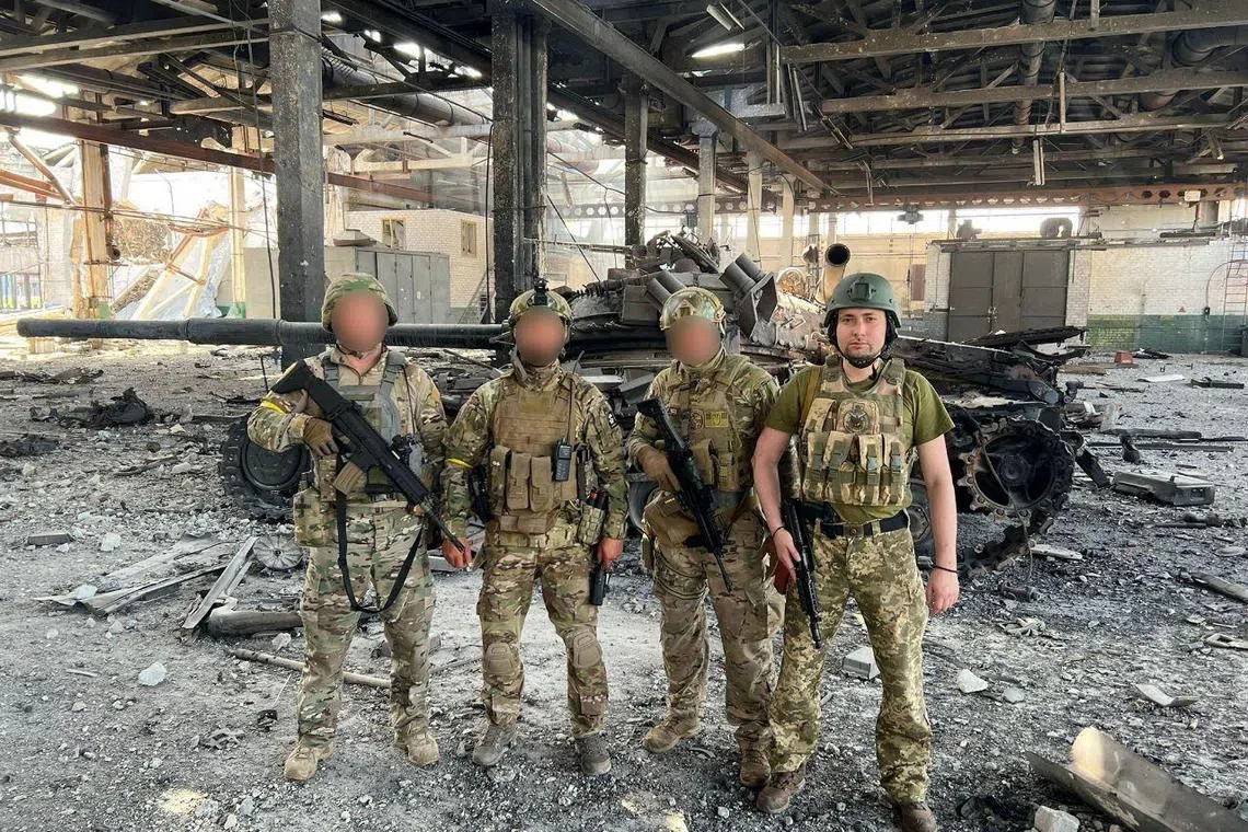 Lt-Gen Kyrylo Budanov (far right) poses for a picture with his brothers-in-arms in front of a destroyed tank, amid Russia's invasion of Ukraine.