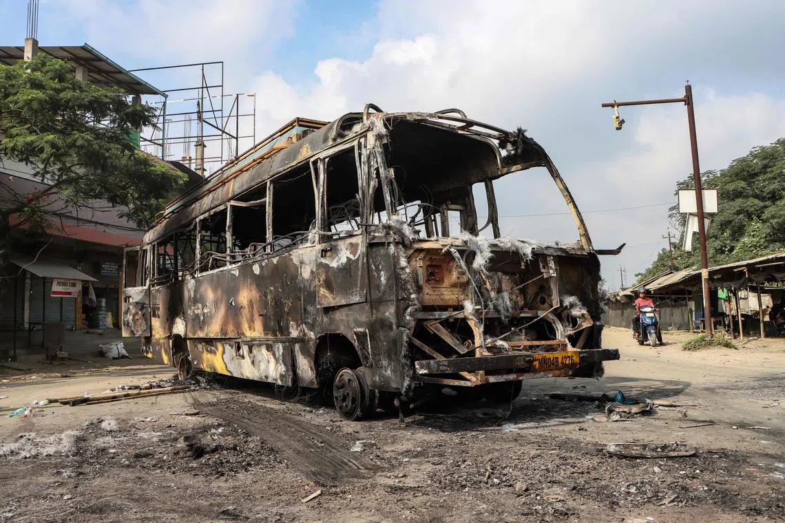 The wreckage of a burned-out bus is pictured along a street after recent violence in Imphal in the Indian state of Manipur on June 8, 2025. (Photo by AFP)