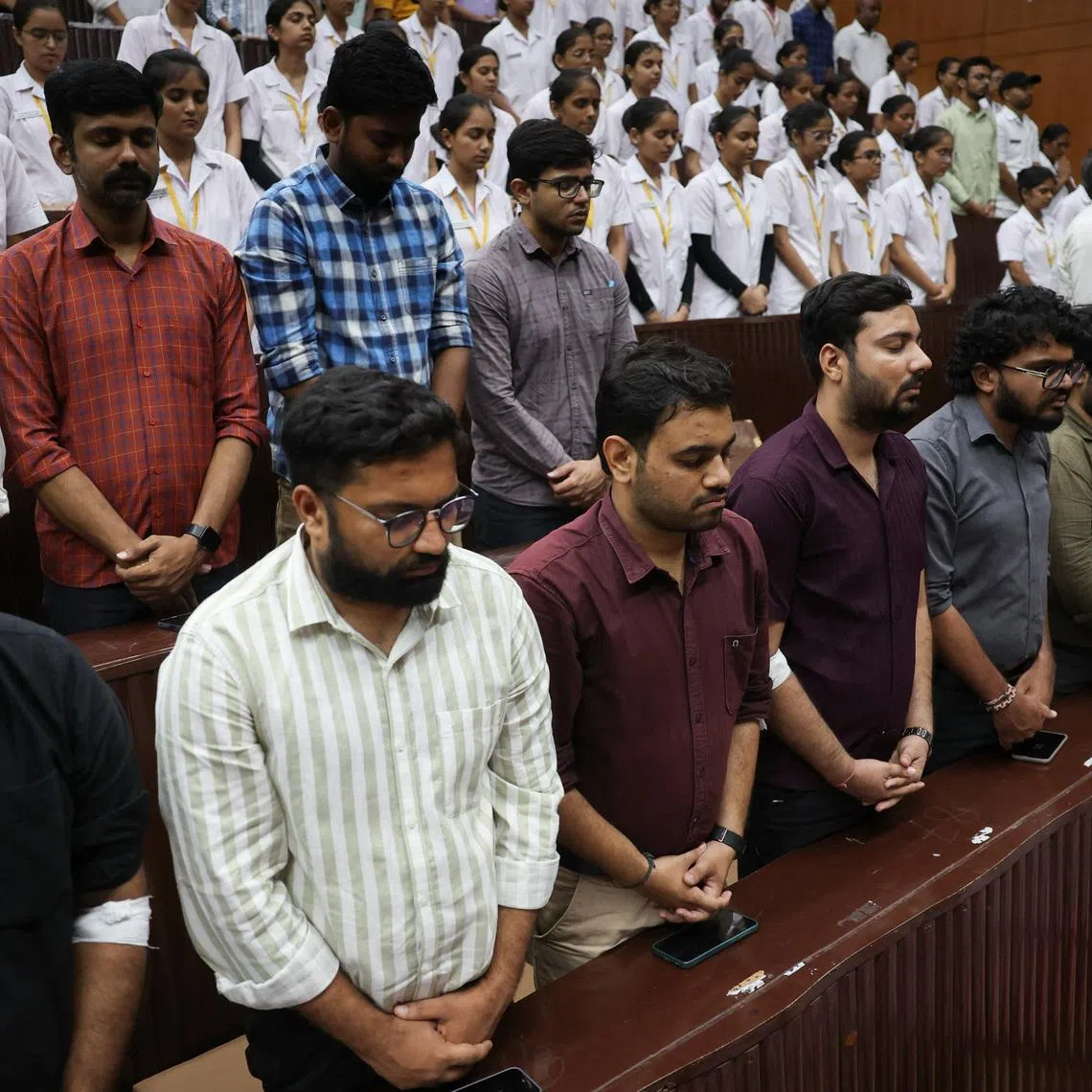 People observe a moment of silence as they attend the memorial ceremony during the first anniversary of Air India Boeing 787-8 Dreamliner crash on June 12, 2025, at B.J. Medical College and Civil hospital in Ahmedabad, India, June 12, 2026. REUTERS/Amit Dave