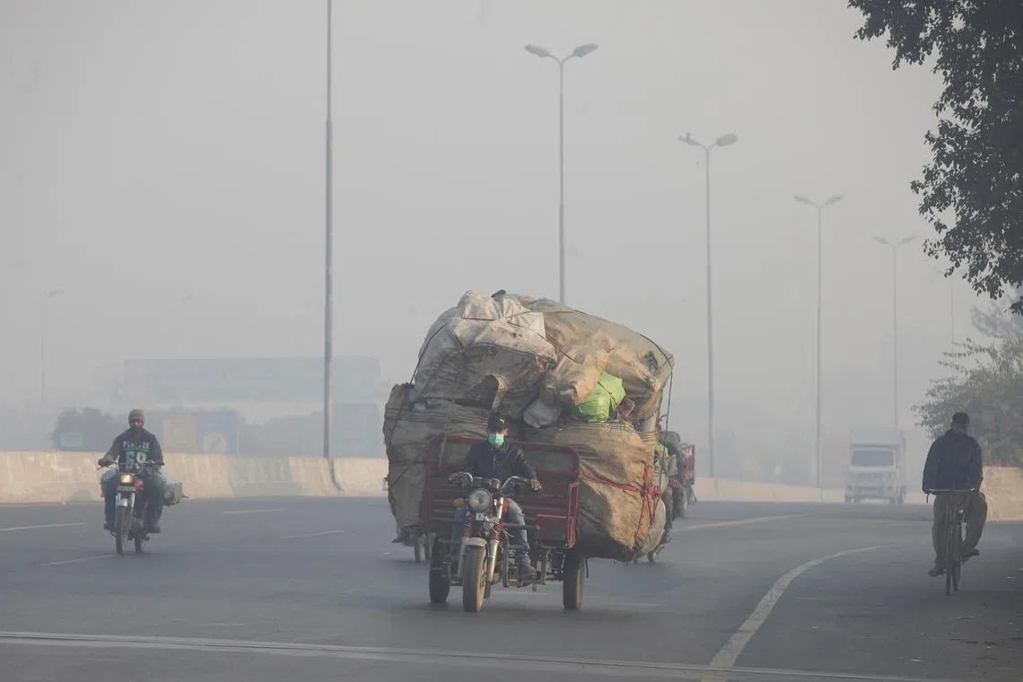 FILE PHOTO: A man rides a motor tricycle, loaded with sacks of recyclables, amid dense smog in Lahore, Pakistan November 24, 2021. REUTERS/Mohsin Raza/File Photo