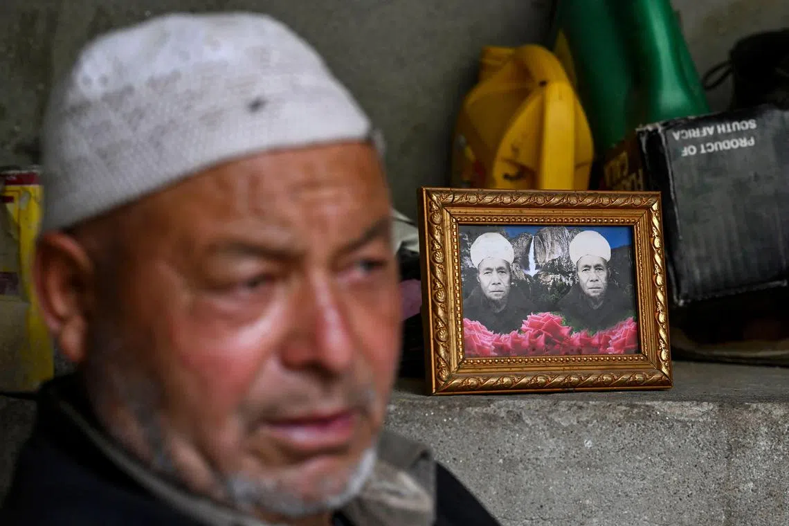 Ghulam Ahmad, an Indian apricot farmer sits beside a portrait of his father who died in Pakistan at the Hunderman village in Kargil district on July 28, 2024.