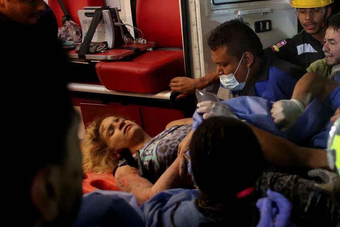 Medical personnel attend to a person lying on a red gurney.