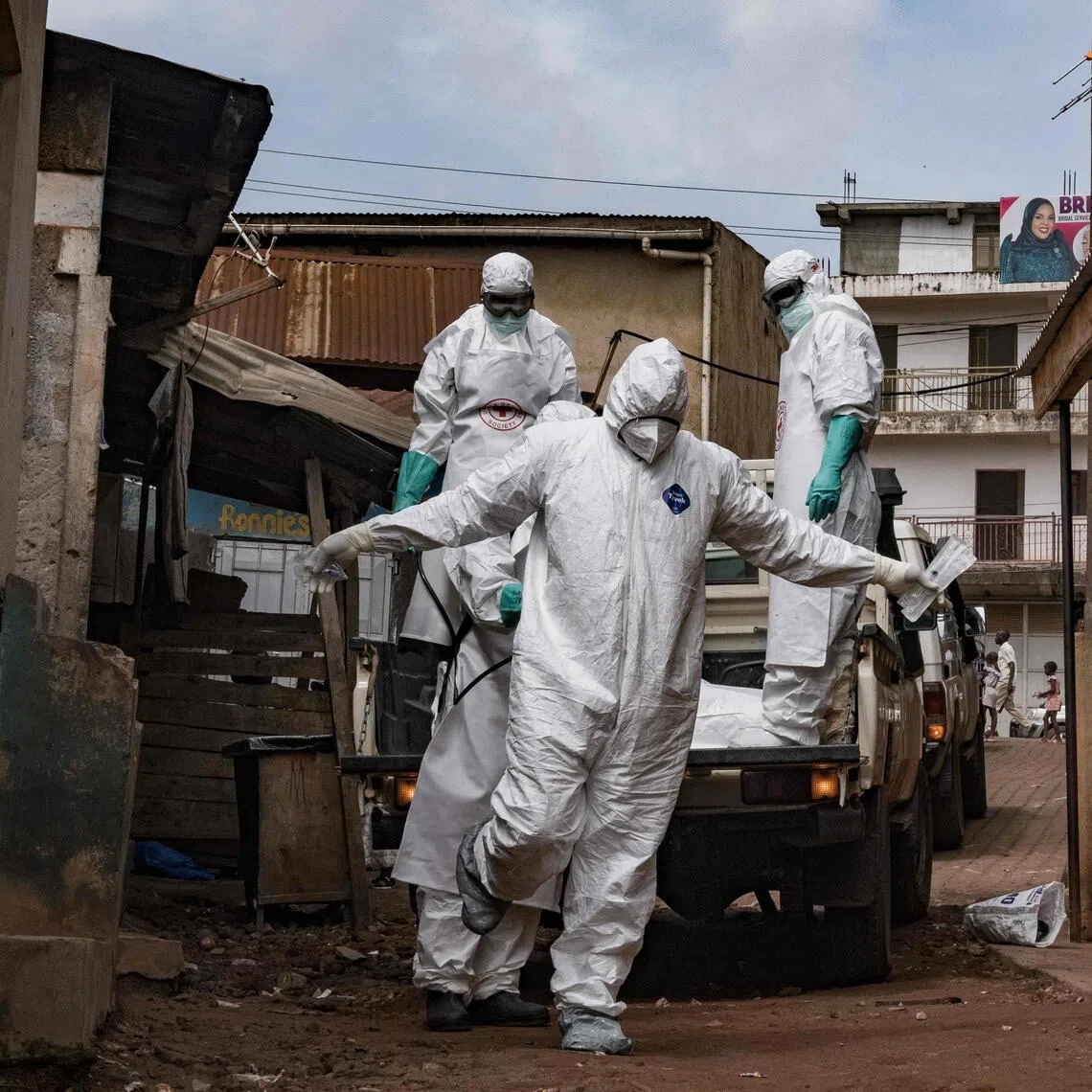 Red Cross workers being sprayed with disinfectant during the evacuation of the body of a suspected Ebola victim in Uganda on May 26.