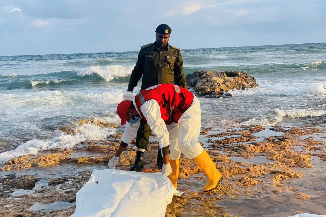 A member of the Red Crescent holds a body bag next to a member of the military in a location given as near Surman, Libya, after a migrant boat capsized west of Libya's capital Tripoli, in this handout image released on October 28, 2025. Libyan Red Crescent Society in Sabratha/Handout via REUTERS