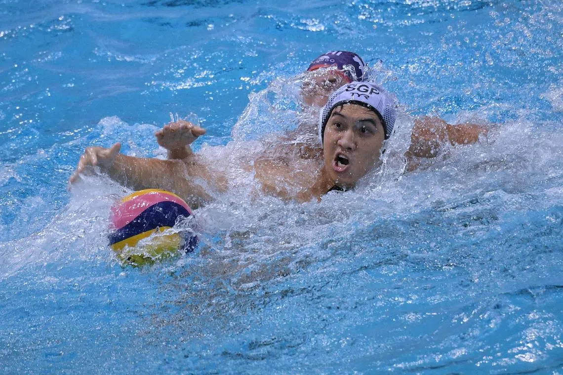 Singapore's Lee Cheng Kang tussles for the ball against a Philippine player during the play-offs at the Asian Water Polo Championships at the OCBC Aquatic Centre on March 26, 2023.