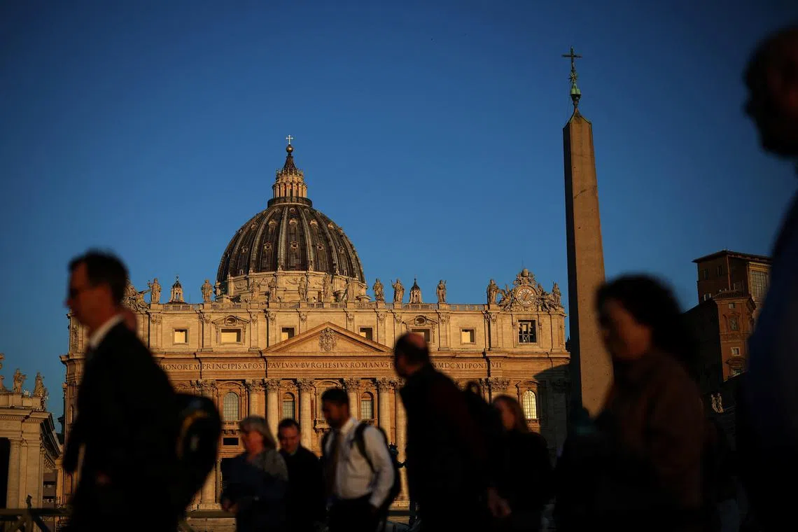 People walk in front of St. Peter's Basilica in St. Peter's Square ahead of the conclave, which will be held on May 7, at the Vatican, April 30, 2025. REUTERS/Stoyan Nenov