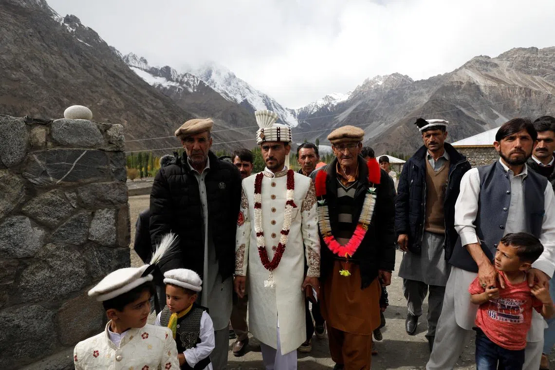 Jaffer Ali Khan, a 31-year-old mason wearing groom's attire, walking with relatives while going to the bride's home during his wedding ceremony in Darkut village, Yasin valley, in the Gilgit-Baltistan region of Pakistan, Oct 13, 2023. 