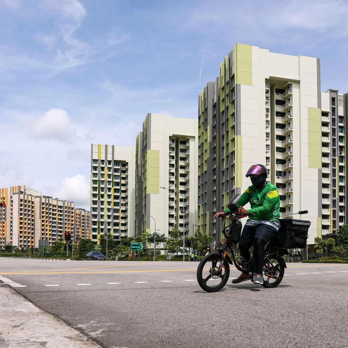 A food delivery rider riding across the road along Tengah Drive, with Parc Flora (left) and Parc Woods (right) estate in the background, on Dec 26, 2025. ST PHOTO: BRIAN TEO