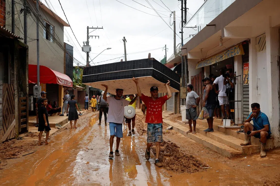 Men carry a mattress on a street covered with mud in one of the landslide sites after severe rainfall at Barra do Sahy, in Sao Sebastiao, Brazil, Feb 21, 2023. 