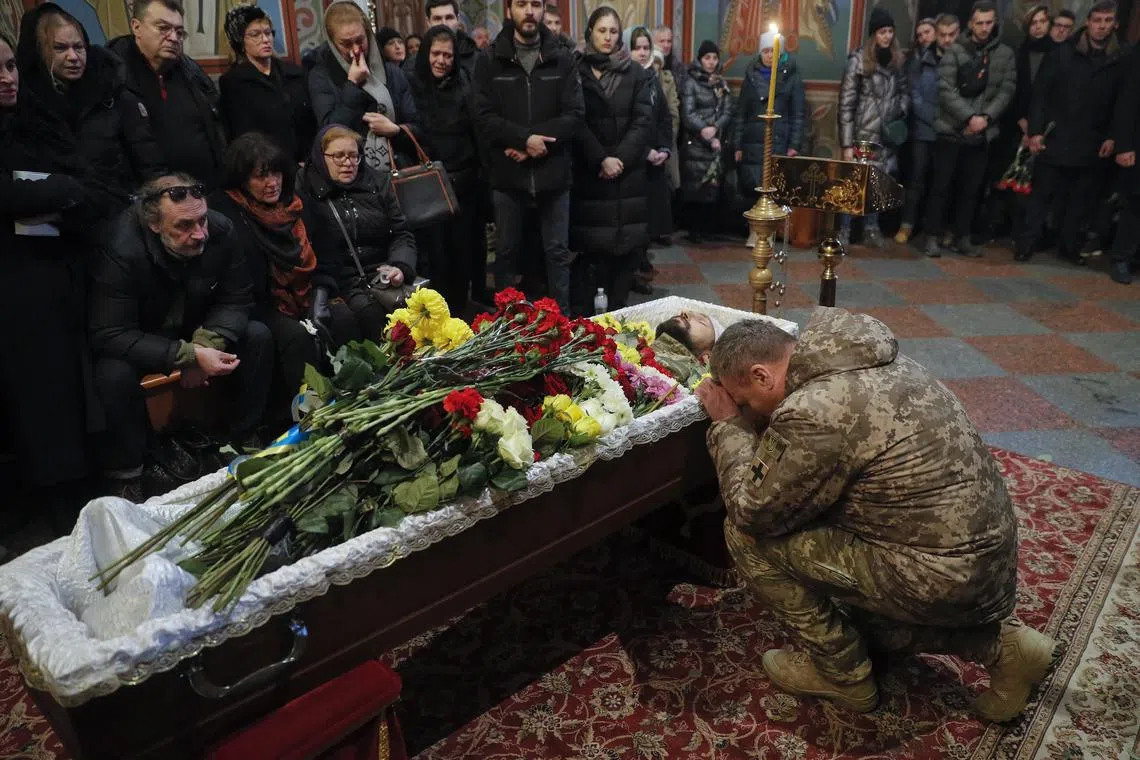  Ukranian soldier mourns next to the coffin of his comrade at a funeral ceremony in Kyiv on Nov 23, 2022.