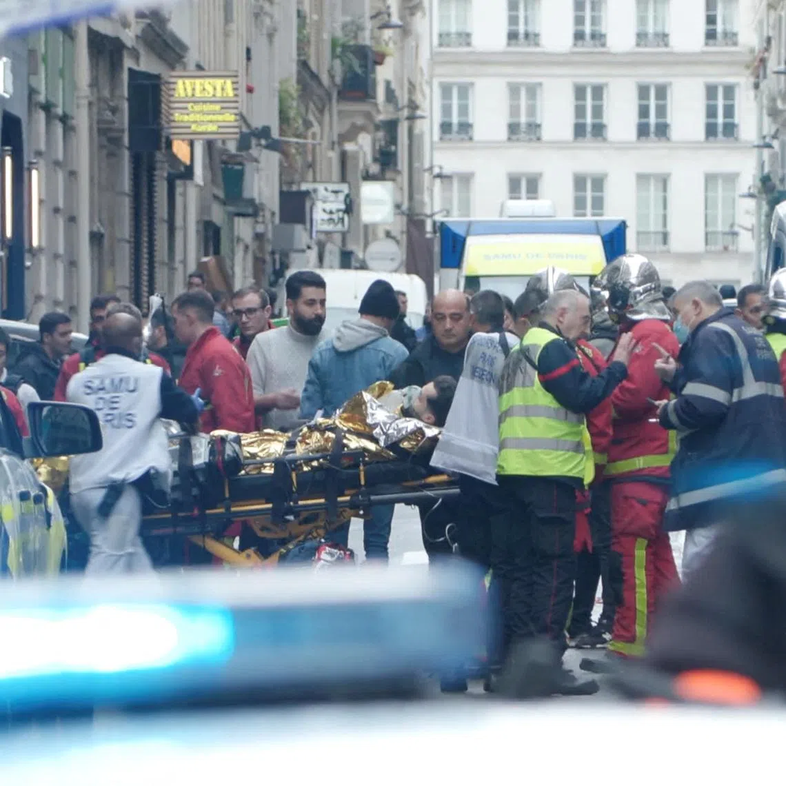 First responders move a man on a gurney after gunshots were fired in central Paris, France, on Dec 23, 2022.