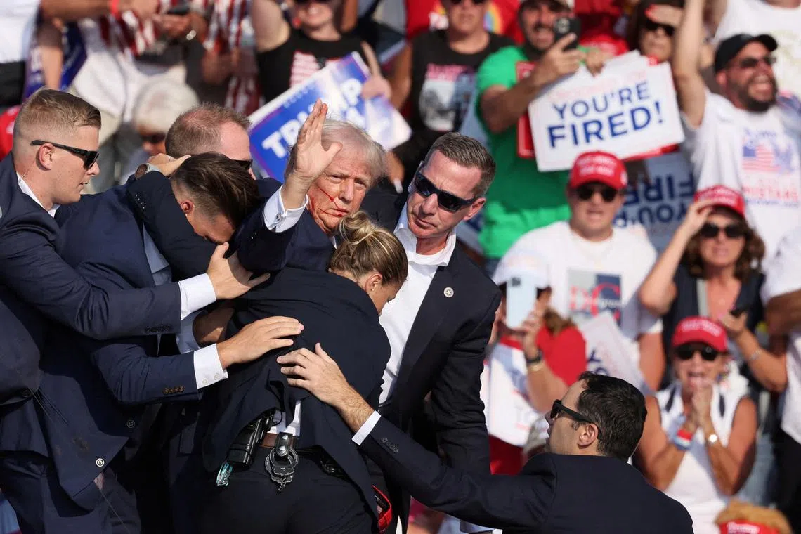 Former US President Donald Trump being assisted by Secret Service personnel after he was shot in the right ear, in Butler, Pennsylvania, on July 13.