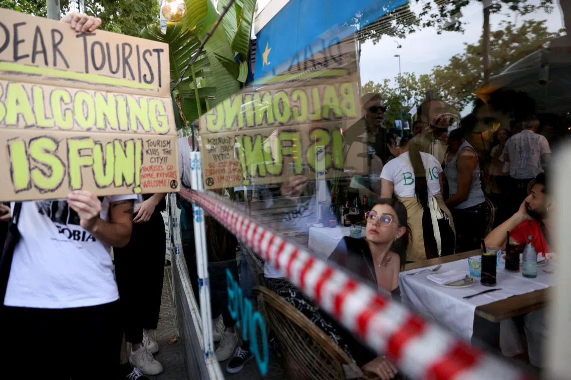 FILE PHOTO: A tourist watches as demonstrators protest against mass tourism in Barcelona, Spain, July 6, 2024. REUTERS/Bruna Casas/File Photo