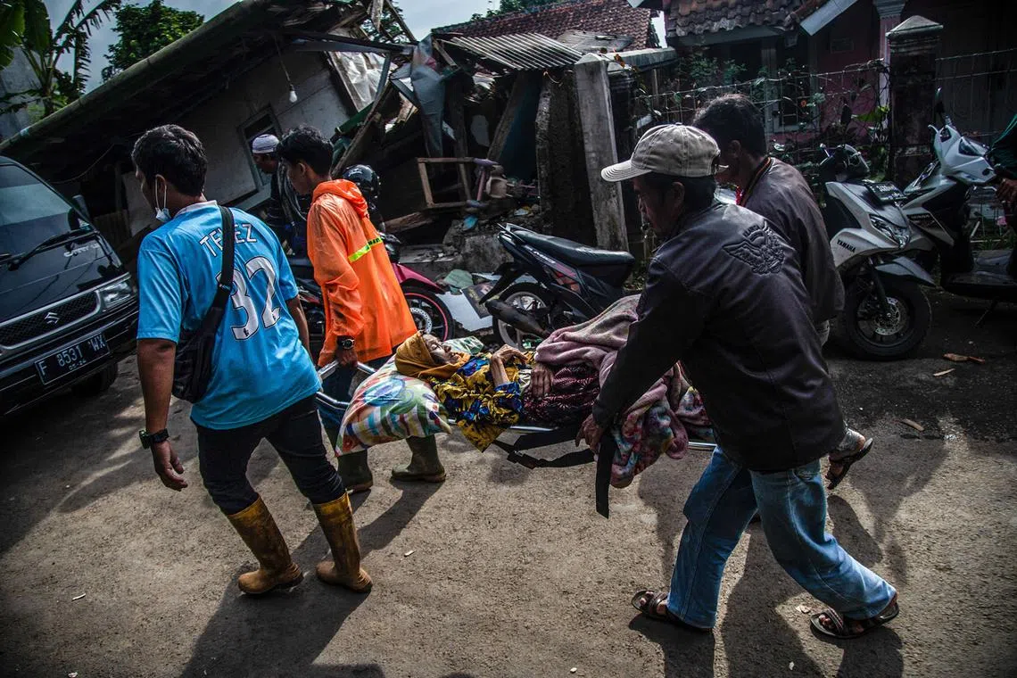 Villagers carry an injured victim following a 5.6-magnitude earthquake that killed at least 162 people, with hundreds injured and others missing in Cianjur on Nov 22, 2022. 